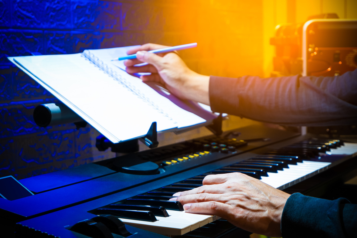 male musician, composer playing piano and writing a hit song in home studio. song writing concept