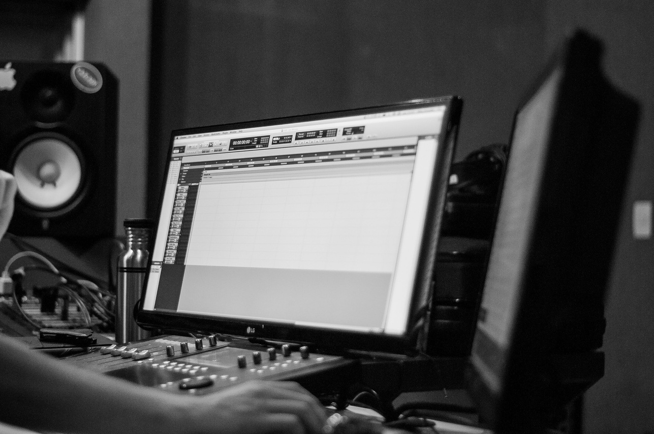 Crop sound engineer working on computer with audio board indoors